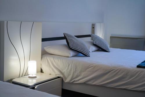 una camera da letto con letto bianco, cuscini e lampada di Hôtel Le Bellevue a Tarascon-sur-Ariège