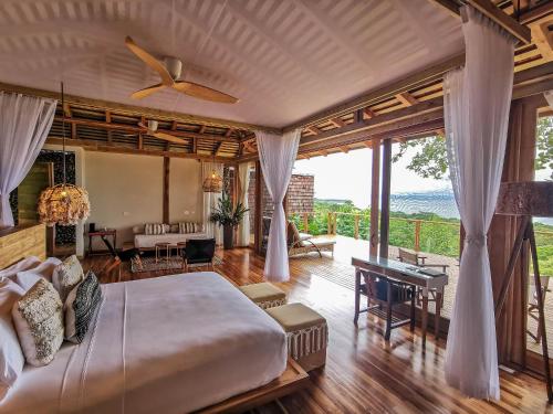 a bedroom with a large bed and a living room at Lapa Rios Lodge by Böëna in Puerto Jiménez