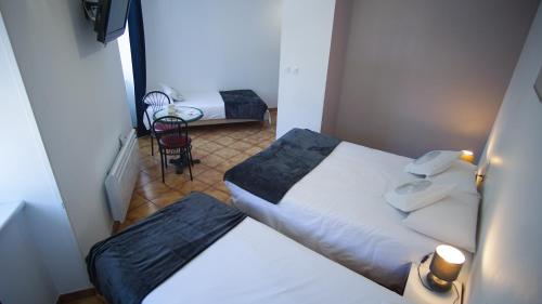 a small room with two beds and a chair at Hôtel Le Bellevue in Tarascon-sur-Ariège