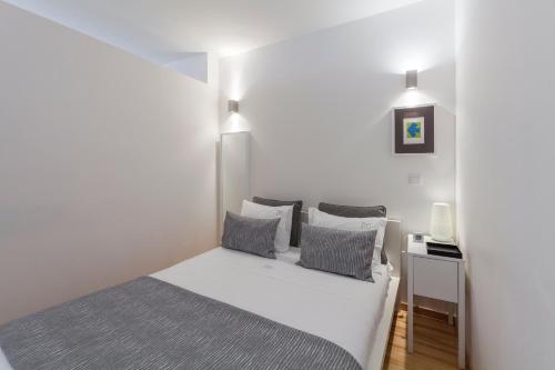 a bedroom with a white bed with gray pillows at BO - Almada in Porto