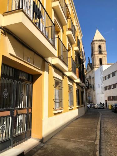 a yellow building on a street with a church at Apartamento La Habana Vieja in Jerez de la Frontera