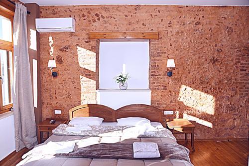 a bedroom with a bed with a brick wall at Santrivani Rooms in Chania Town