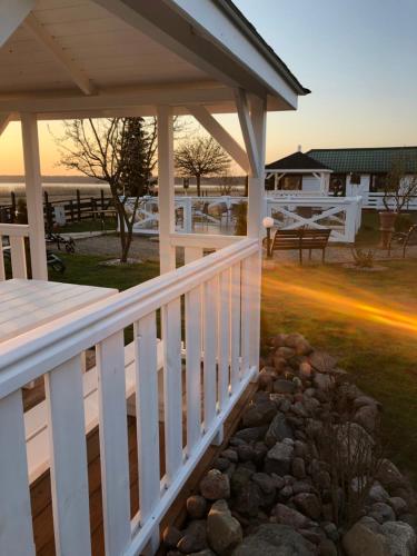 a porch with a white railing and a rock garden at Avila Park & SPA in Dziwnówek