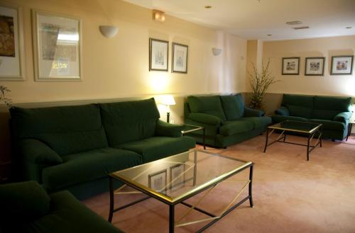 a living room with green couches and a glass table at Motel Jardin in Oleiros