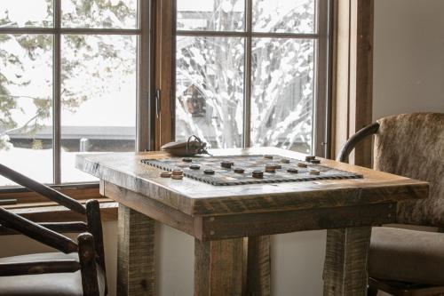 a wooden table in front of a window with a chess board on it at Hobbit House in Big Sky