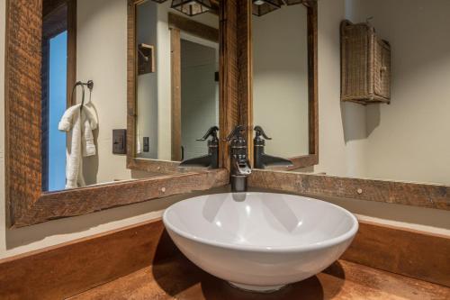 a white sink in a bathroom with two mirrors at Hobbit House in Big Sky