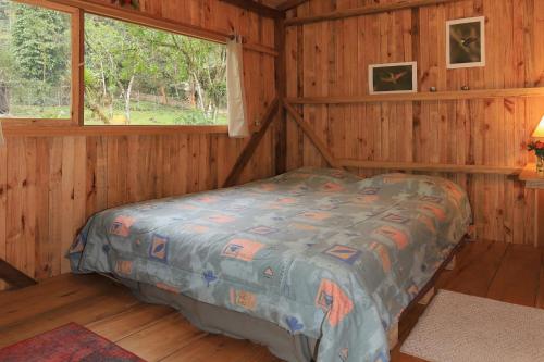 a bedroom with a bed in a wooden cabin at Mindo Eco Suite con Rio y Cascada in Mindo