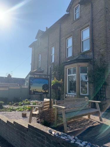 a wooden bench sitting in front of a building at Craiglands Bed and Breakfast, Grassington in Grassington