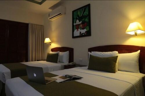 a hotel room with two beds with a laptop on it at Tabasco Inn in Villahermosa
