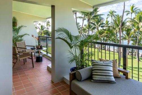 a living room with a couch and a balcony with palm trees at Shangri-La Yanuca Island, Fiji in Voua