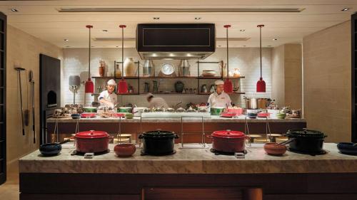 a kitchen with three chefs preparing food in a restaurant at Shangri-La Rasa Ria, Kota Kinabalu in Kota Kinabalu