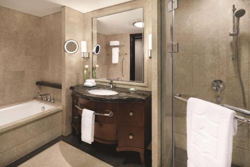 a bathroom with a sink and a tub and a mirror at Shangri-La Jakarta in Jakarta