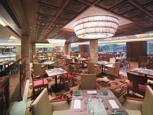 a restaurant with tables and chairs and a large chandelier at Kowloon Shangri-La, Hong Kong in Hong Kong
