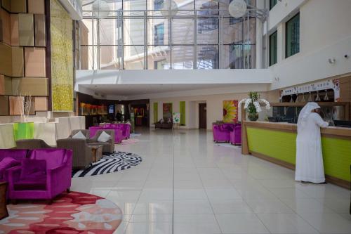 a lobby with purple chairs and a woman standing at a counter at Traders Hotel, Abu Dhabi in Abu Dhabi