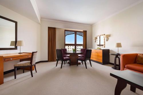 a living room with a desk and a table and chairs at Shangri-La Barr Al Jissah, Muscat in Muscat