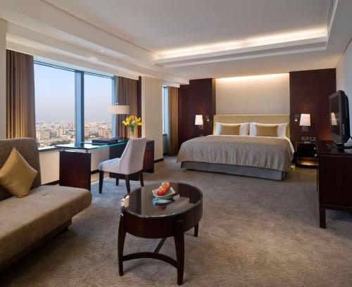 a hotel room with a bed and a couch and a table at Shangri-La Far Eastern Tainan in Tainan