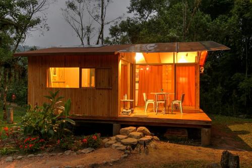 a small wooden cabin with a table and chairs at Mindo Eco Suite con Rio y Cascada in Mindo