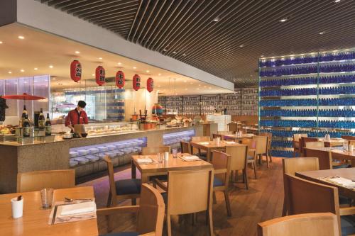 a restaurant with tables and chairs and a chef in the kitchen at Shangri-La Qingdao - May Fourth Square in Qingdao