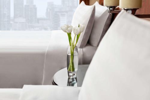 a vase of flowers on a table next to a bed at Shangri-La Suzhou in Suzhou
