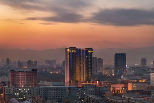 a view of a city at sunset with buildings at Shangri-La Huhhot in Hohhot