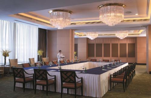 a man standing in a room with a long table at Shangri-La Huhhot in Hohhot