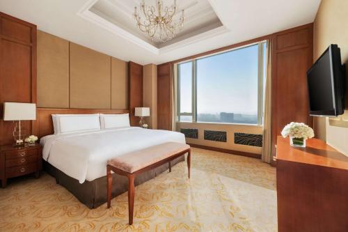 a bedroom with a bed and a large window at Shangri-La Huhhot in Hohhot