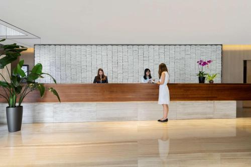 a woman standing at a counter in a lobby at Jen Hong Kong by Shangri-La in Hong Kong