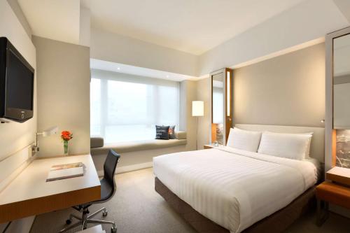 a hotel room with a bed and a desk and a window at Jen Hong Kong by Shangri-La in Hong Kong