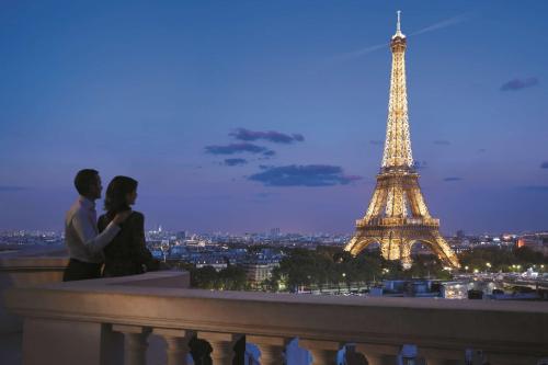 a couple sitting on a ledge in front of the eiffel tower at Shangri-La Paris in Paris
