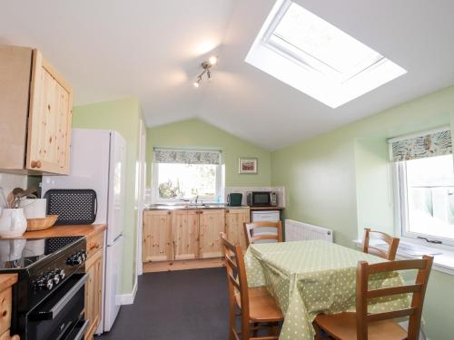 a kitchen with a table and a white refrigerator at Balnaird Farmhouse in Strathpeffer