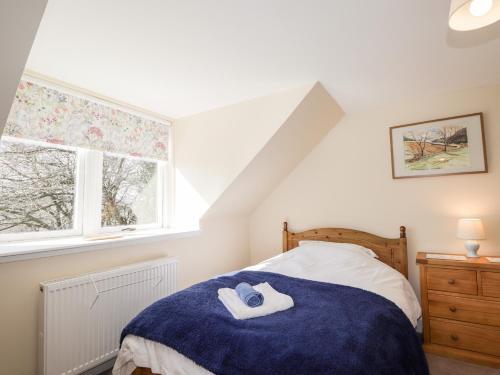 a bedroom with a bed with two towels on it at Balnaird Farmhouse in Strathpeffer