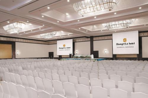 an empty hall with white chairs and two screens at Shangri-la Surabaya in Surabaya