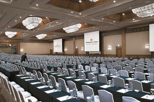a large room with chairs and a man standing in the middle at Shangri-la Surabaya in Surabaya
