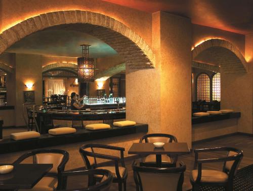 a restaurant with a bar with chairs and tables at Shangri-la Surabaya in Surabaya