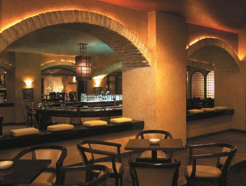 a restaurant with a bar with chairs and tables at Shangri-la Surabaya in Surabaya