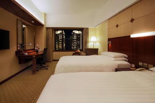 a hotel room with two beds and a desk and a window at Shangri-La Harbin in Harbin