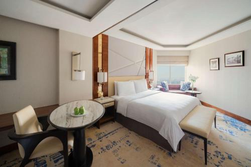 a bedroom with a large bed and a table at Shangri-La Eros New Delhi in New Delhi