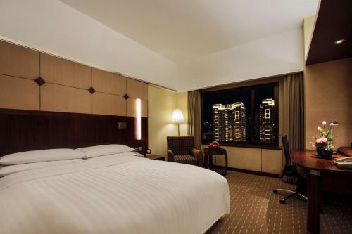 a hotel room with a large bed and a desk at Shangri-La Harbin in Harbin