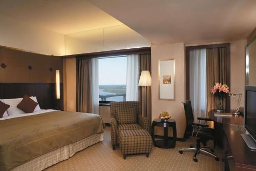 a hotel room with a bed and a desk and a chair at Shangri-La Harbin in Harbin