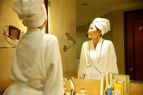 a woman looking at her reflection in a bathroom mirror at Shangri-La Harbin in Harbin