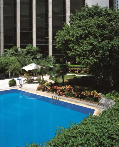 a blue swimming pool in front of a building at Shangri-La Shenzhen - Nearby Luohu Border, Outdoor Swimming Pool in Shenzhen