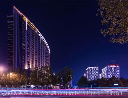 a hotel is lit up at night with buildings at Shangri-La Baotou in Baotou