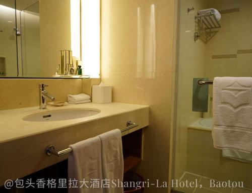 a bathroom with a sink and a mirror and a shower at Shangri-La Baotou in Baotou