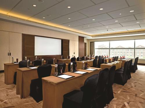a conference room with tables and chairs and a screen at Kerry Hotel Pudong, Shanghai - Indoor Connecting to Shanghai New International Expo Centre in Shanghai