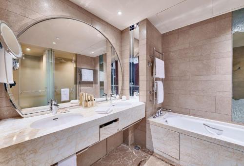 a bathroom with two sinks and a tub and a mirror at Shangri-La Tianjin in Tianjin