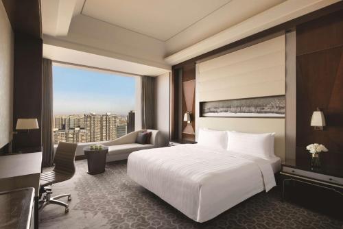 a bedroom with a large white bed and a large window at Shangri-La Tangshan in Tangshan
