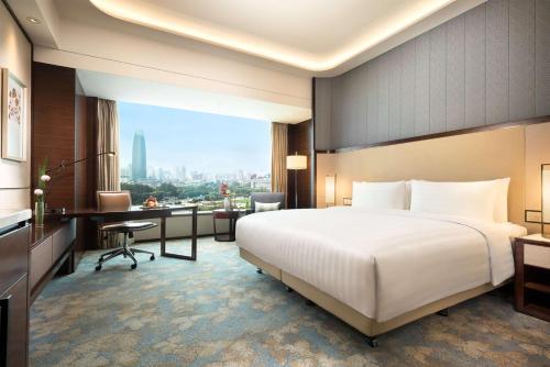 a hotel room with a large bed and a desk at Shangri-La Jinan in Jinan