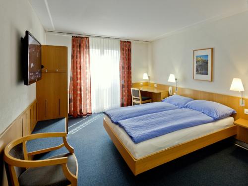 ein Hotelzimmer mit einem Bett und einem Schreibtisch in der Unterkunft Good Night Inn in Brig