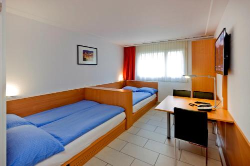 a bedroom with two beds and a desk with a computer at Good Night Inn in Brig