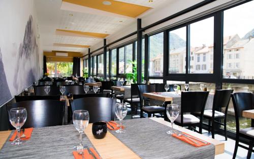 a restaurant with tables and chairs and windows at Hôtel Le Bellevue in Tarascon-sur-Ariège
